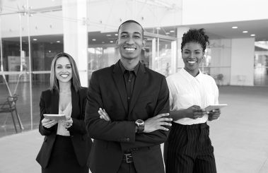 51. Building Strategic Partnerships for the Globalization of Revenue Cycle Management – happy-cheerful-business-people-posing-office-hallway Building Strategic Partnerships for the Globalization of Revenue Cycle Management